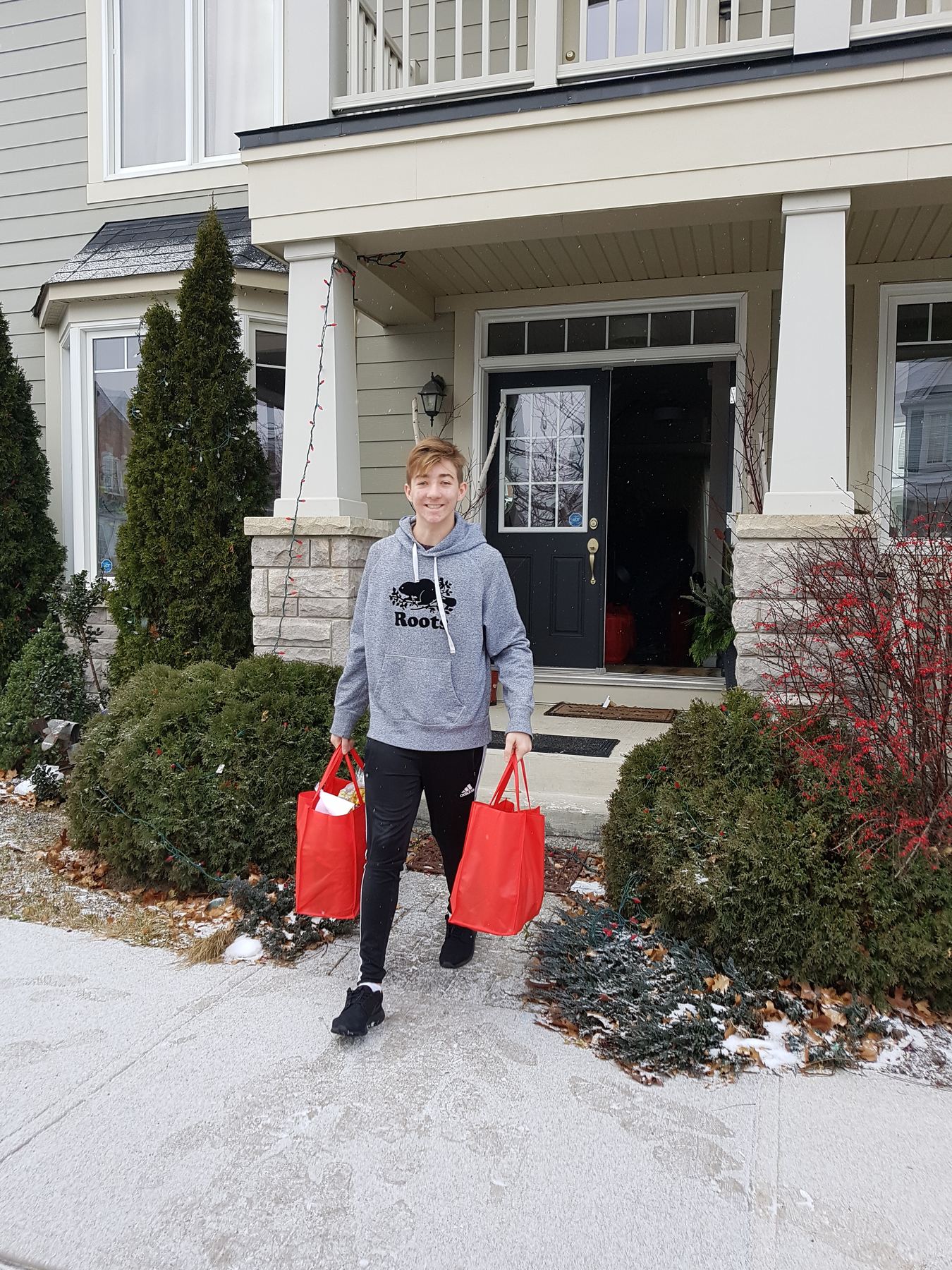 A volunteer delivering two filled red bags at a doorstep