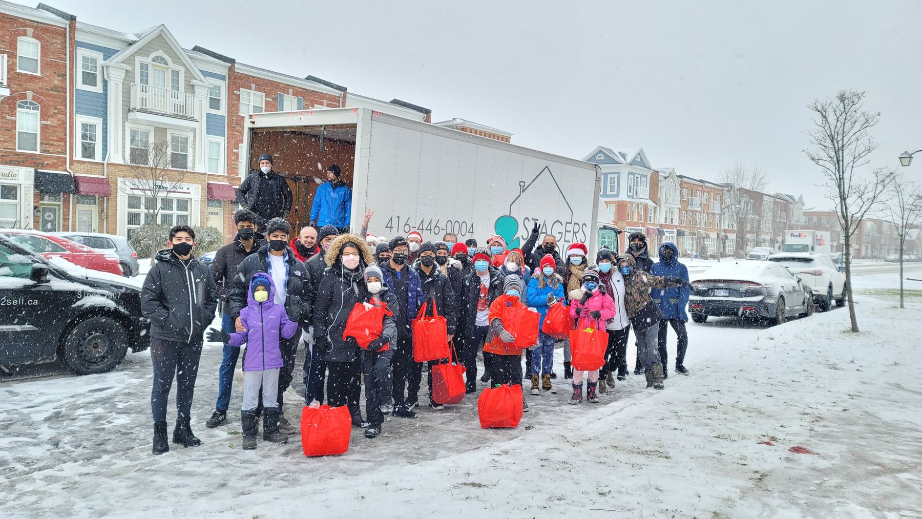 Red Bags volunteers gathered with filled red bags beside the delivery truck in the snow